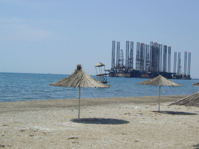 beach on caspian with oil derricks